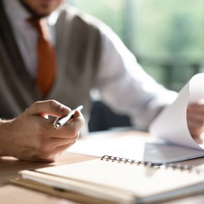 Businessman hands holding pen for working with stack of paper files, searching information, business report